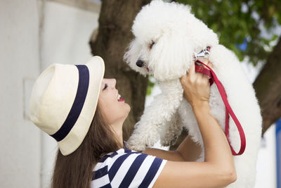 Portrait of woman with dog against white hat