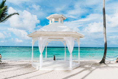 White gazebo at beach against cloudy sky