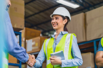 Smiling engineer shaking hand with co worker at warehouse