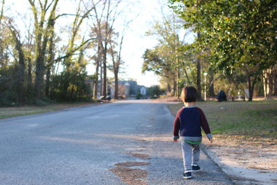 Rear view of boy walking on road
