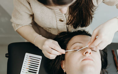 Portrait of a girl cosmetologist extending eyelashes to a woman.