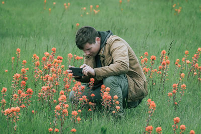 Rear view of man photographing on field