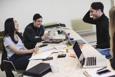 Four happy people sitting at desk in office