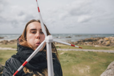 France, brittany, meneham, young woman with miniature wind turbine at the coast