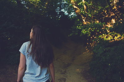 Rear view of woman standing at forest