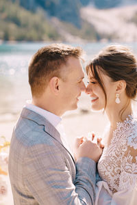 Smiling bridegroom embracing while standing outdoors