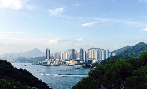 View of skyscrapers by sea against sky