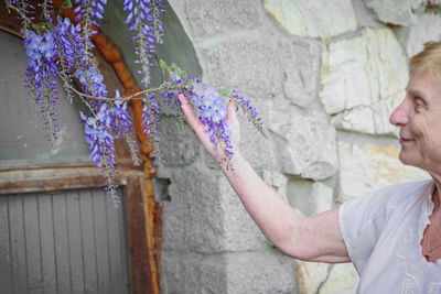 Elderly woman looking at blooming wisteria branches