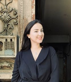 Portrait of young woman standing against wall