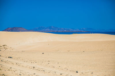 Scenic view of desert against clear blue sky