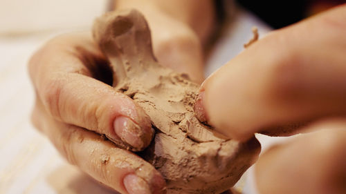 Cropped hands of craftsperson making clay product in pottery workshop