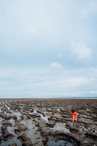 Girl walking at beach against sky