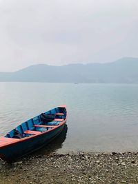 Boat moored on lake against sky