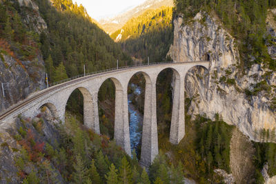 Arch bridge over river against mountains