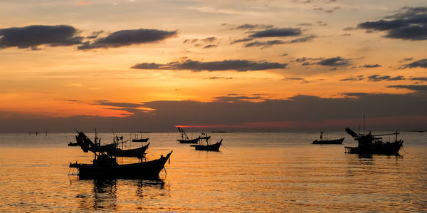 Silhouette boats in sea against sky during sunset