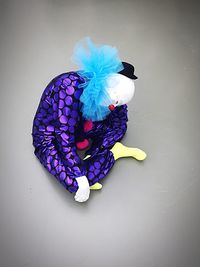 High angle view of sad clown sitting over gray background