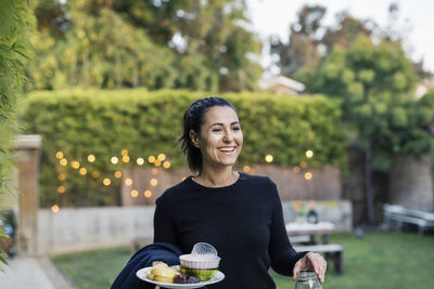 Happy woman holding plate at yard