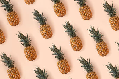 A bright pattern of many pineapples on a trendy soft beige pink background. tropical juicy fruits