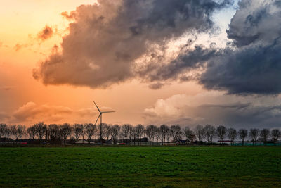 Windmill on field against sky during sunset