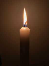 Close-up of illuminated candle in darkroom