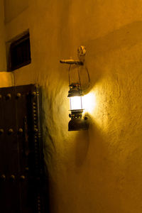 Low angle view of illuminated lamp mounted on wall