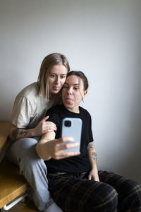 Young lesbians taking selfie through smart phone while sticking tongue out