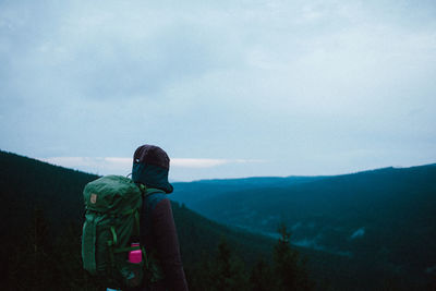 Rear view of backpack man looking at mountain against sky