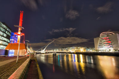 Illuminated bridge over river with buildings in background