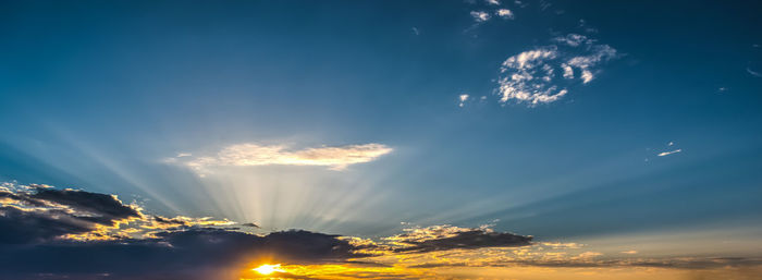 Low angle view of sunlight streaming through clouds