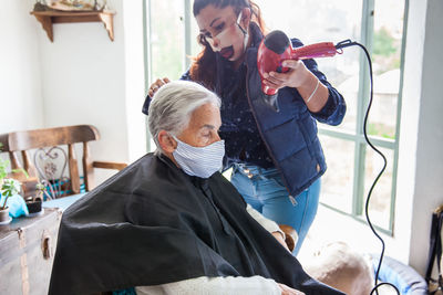 Beautician treating hair of customer at home