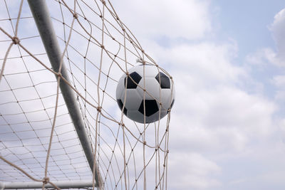 Low angle view of soccer ball on net against sky