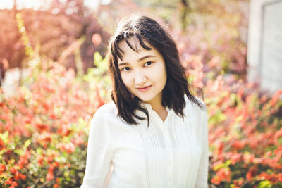 Cheerful asian young woman in a white blouse in a blooming park