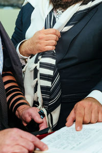 Midsection of people reading torah in yarmulke