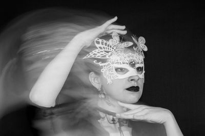 Blurred motion of woman wearing mask against black background