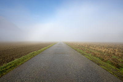 Road amidst agricultural field against sky