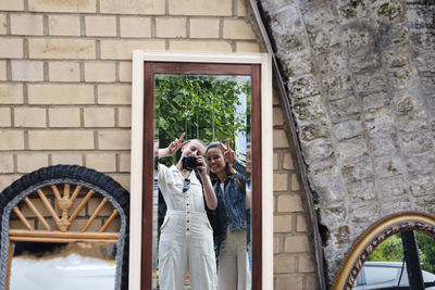 Smiling friends taking mirror selfie