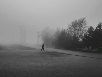 Silhouette man walking on road against sky