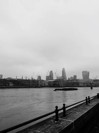 Skyscrapers by thames river against sky