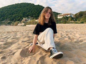 Teenager girl sitting at the beach and looking into camera, copy space