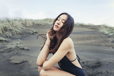 Close-up of beautiful woman crouching on wet beach