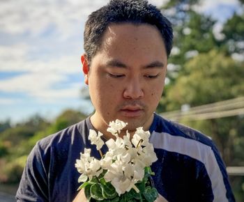 Close-up portrait of young man with red flower