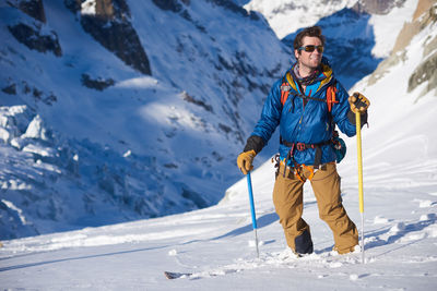 Smiling skier in blue jacket stood still on a glacier descent