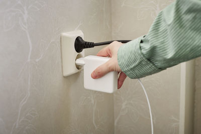 Hand plugging in or out electric cord into socket