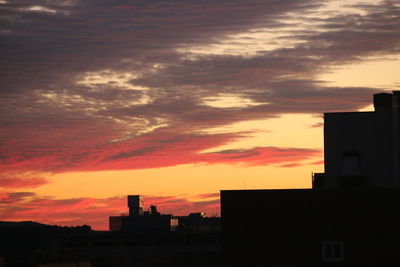 Silhouette buildings in city against sky during sunset