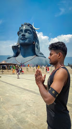 Man standing by statue against sky