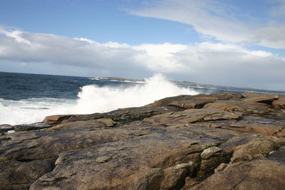 Waves splashing on shore against sky