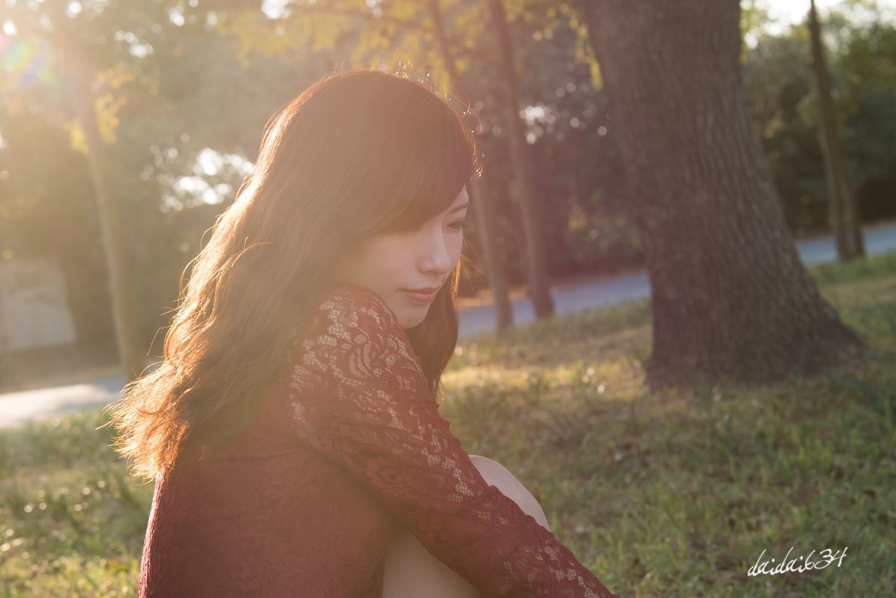 one person, tree, real people, leisure activity, young adult, side view, focus on foreground, sunlight, young women, park - man made space, outdoors, lifestyles, day, nature, beautiful woman, happiness, grass, close-up