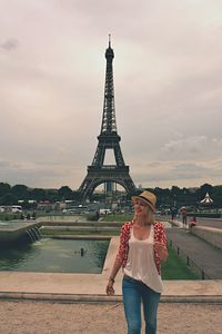 Beautiful woman standing against eiffel tower at dusk