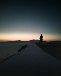 Silhouette woman looking at sea against sky during sunset