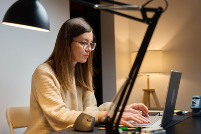 Young woman using mobile phone while sitting at home